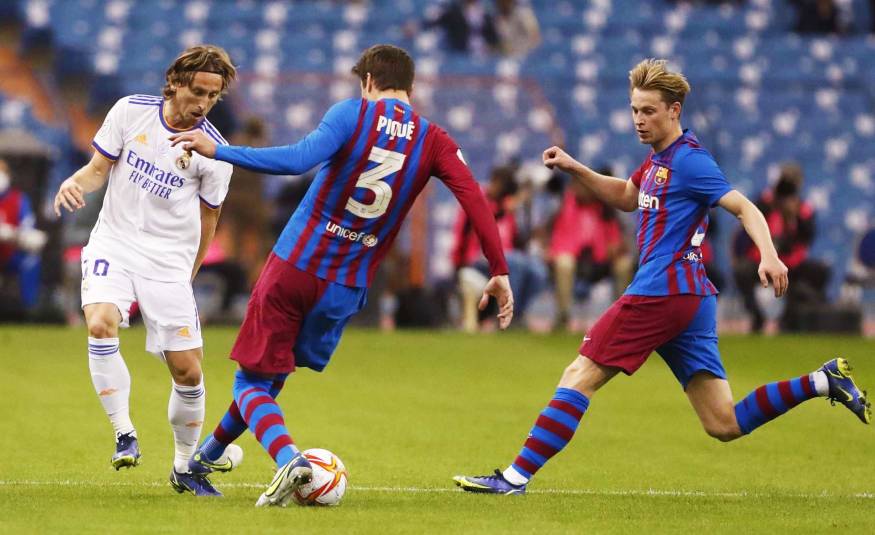 Real Madrids Luca Modric im Clasico gegen Barcelonas Gerard Piqué und Frenkie de Jong (12.01.2022)